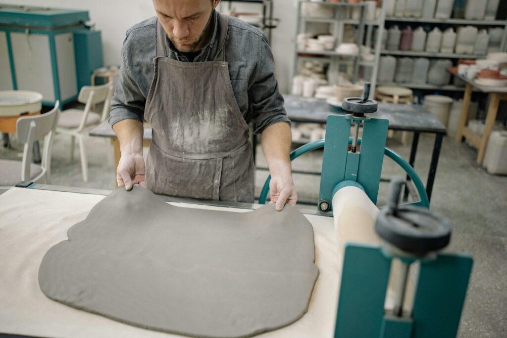 A craftsman shaping clay on a table in a professional workshop, showcasing traditional handmade techniques.